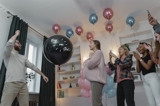 Group of friends celebrating a gender reveal party with balloons and excitement indoors.