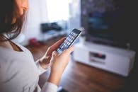 Woman browsing smartphone indoors, highlighting modern technology and communication in a cozy home setting.